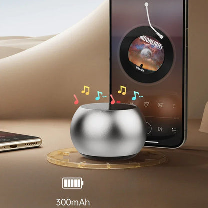 Mini enceinte portable argentée avec icônes de musique colorées, à côté d'un smartphone jouant Moonlight