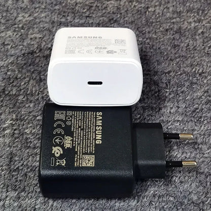 Deux chargeurs Samsung, un blanc USB-C et un noir prise européenne, posés sur une surface texturée grise