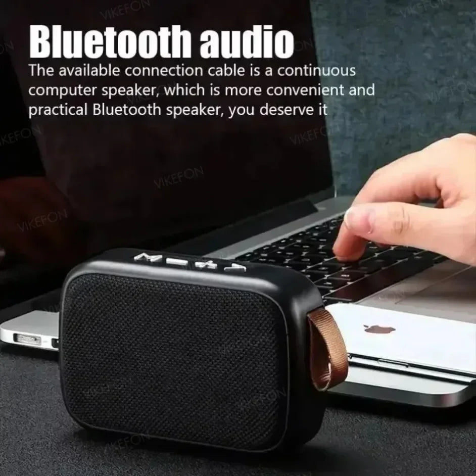 Haut-parleur Bluetooth noir portable posé près d'un ordinateur portable MacBook argent avec une main sur le clavier