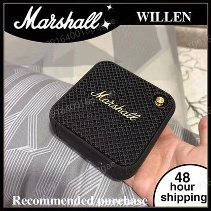 Enceinte portable Marshall noire avec design classique tenue en main sur fond de tissus gris