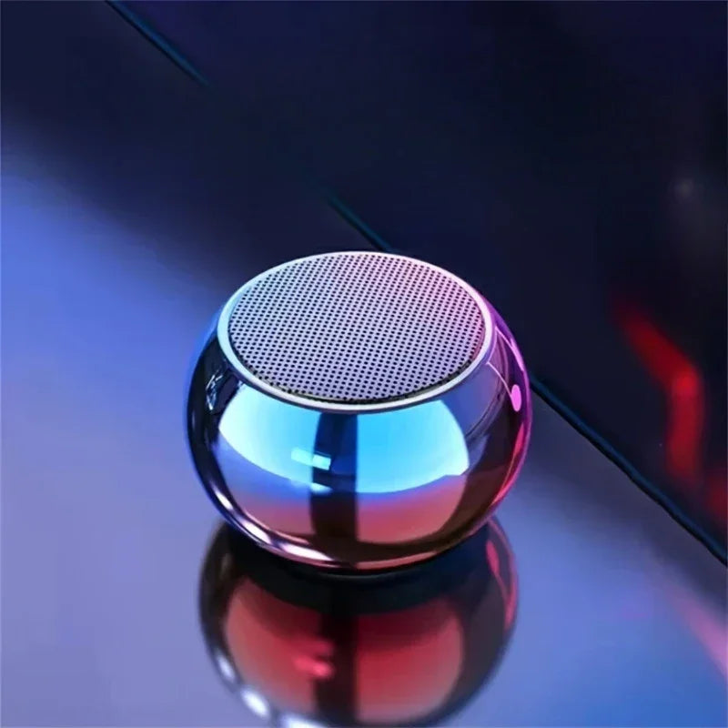 Enceinte Bluetooth portable ronde avec finition métallique et éclairage bleu et rose sur surface brillante