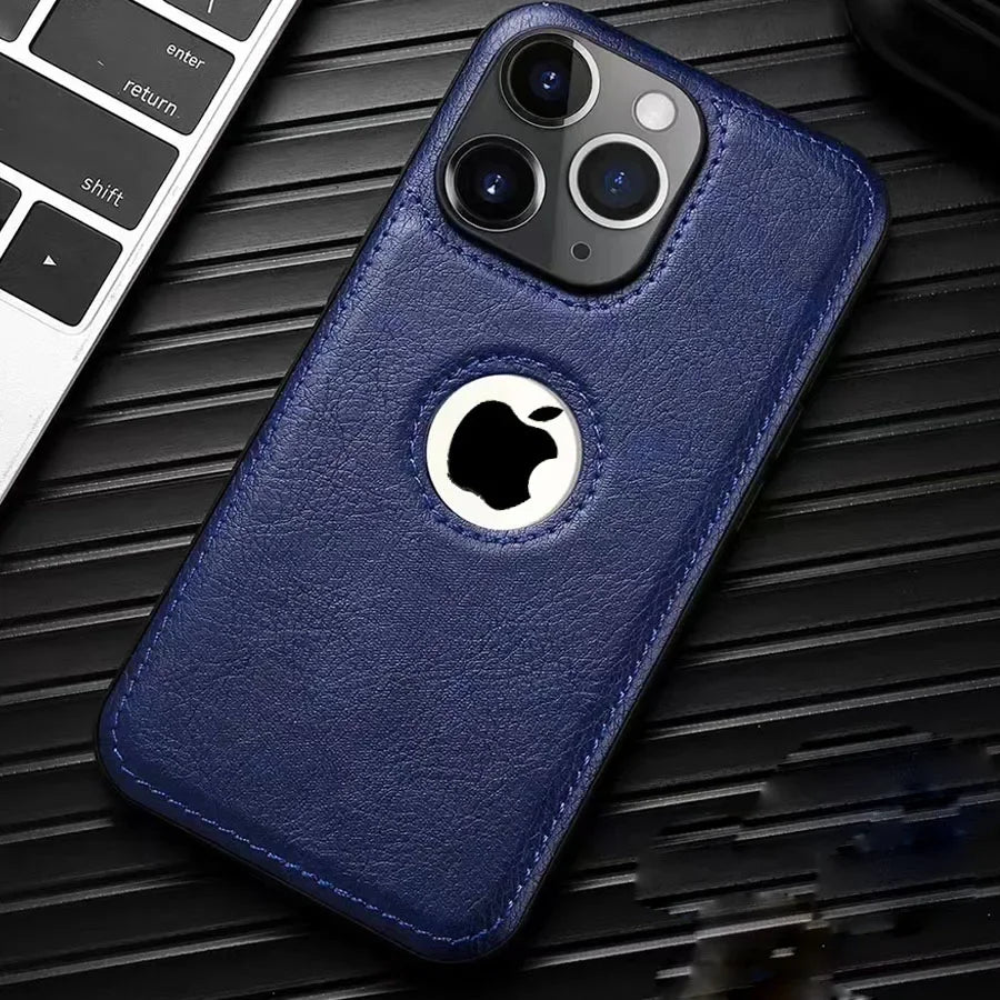 Coque iPhone bleu en cuir avec découpe logo Apple sur fond noir à côté d'un clavier d'ordinateur