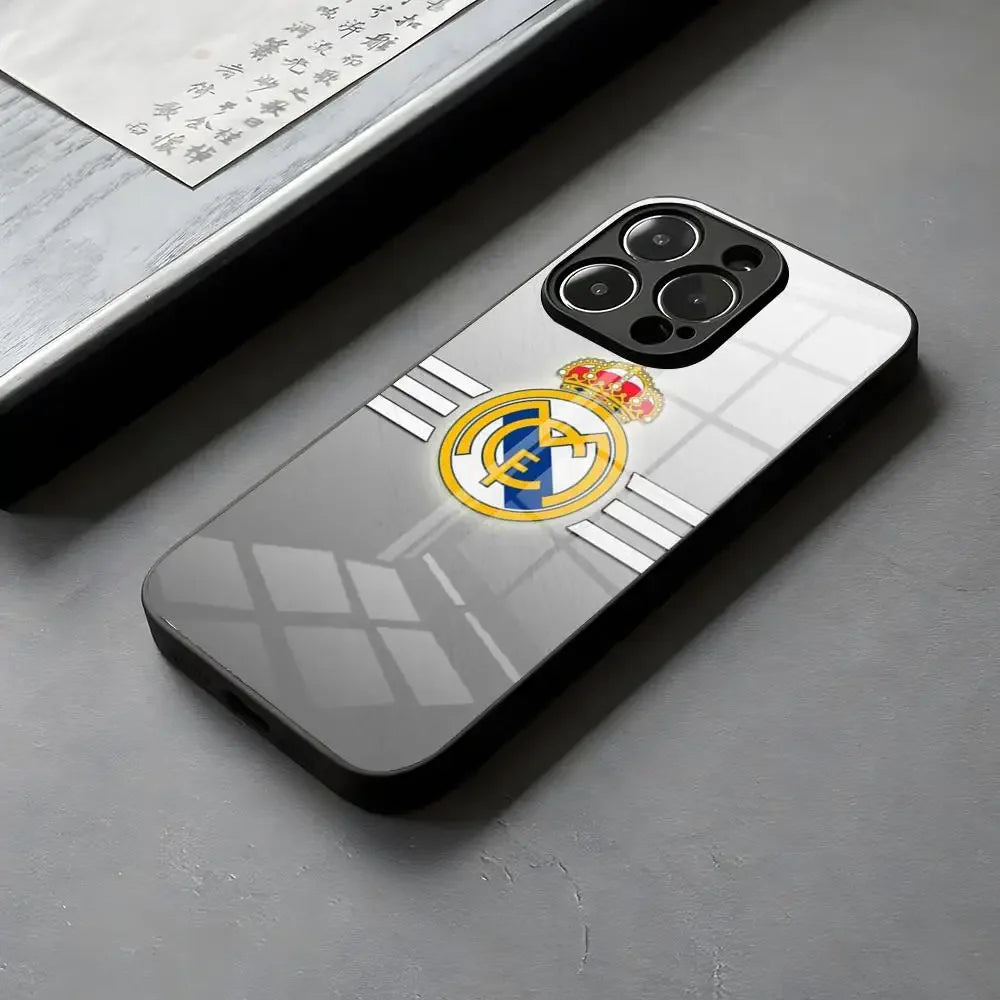 Coque de téléphone grise avec le logo du Real Madrid, posé sur une surface grise près d'un document