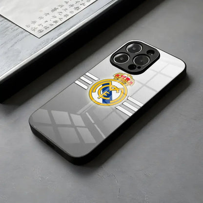 Coque de téléphone grise avec le logo du Real Madrid, posé sur une surface grise près d'un document