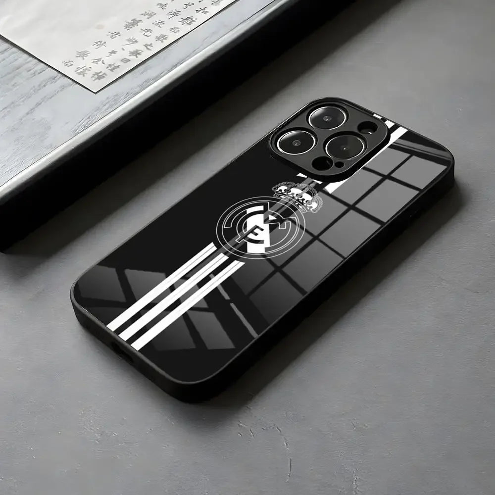 Coque de téléphone noire brillante avec logo Real Madrid et bandes blanches sur surface grise