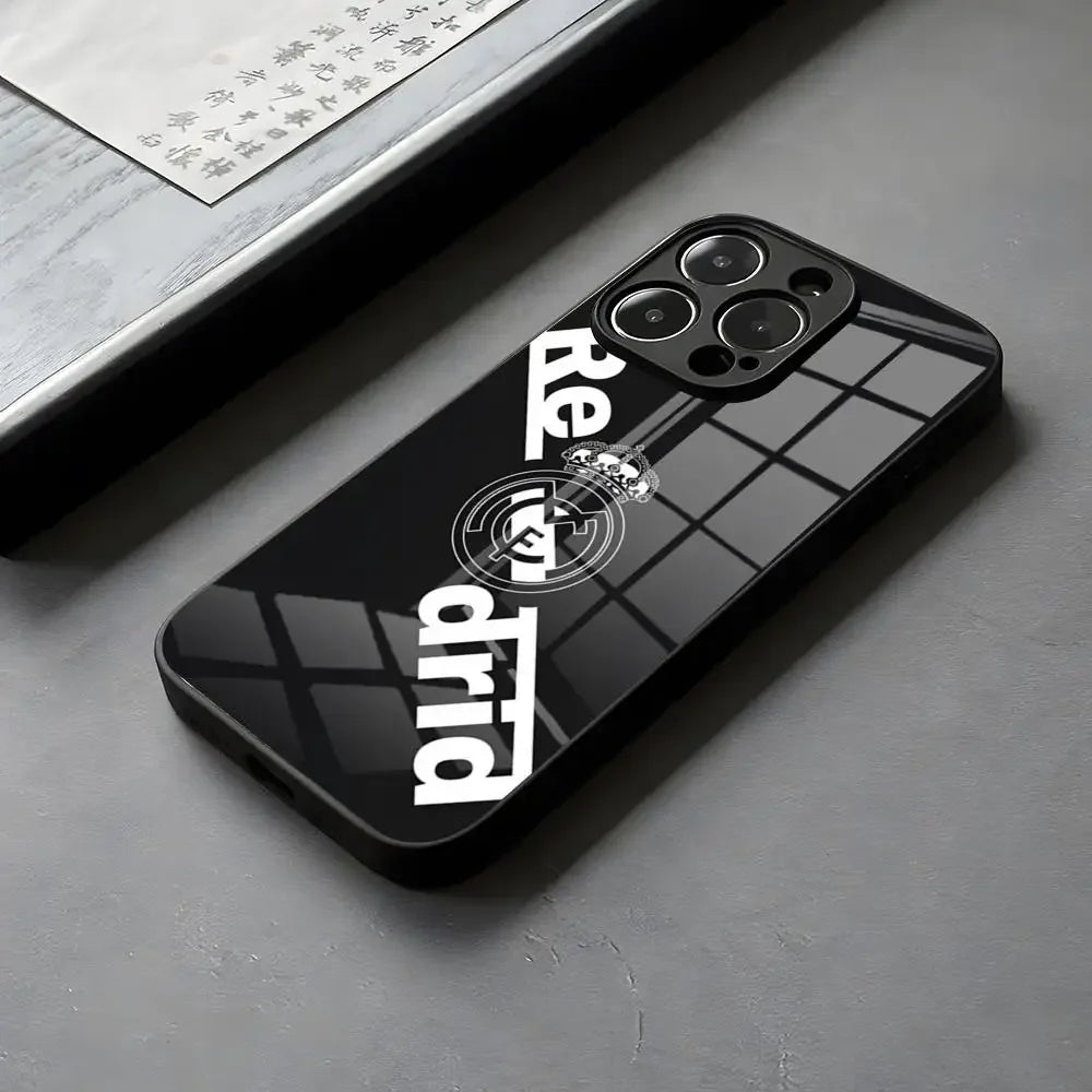 Coque de téléphone noire brillante avec logo Real Madrid et reflet de fenêtre sur surface grise