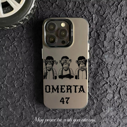 Coque de téléphone gris avec illustration de trois singes stylisés et texte Omerta 47 sur fond asphalté