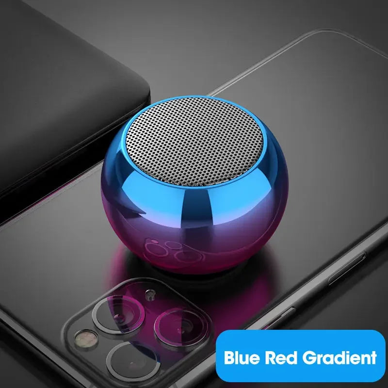 Mini enceinte Bluetooth sphérique avec dégradé bleu rouge posée sur smartphone noir moderne