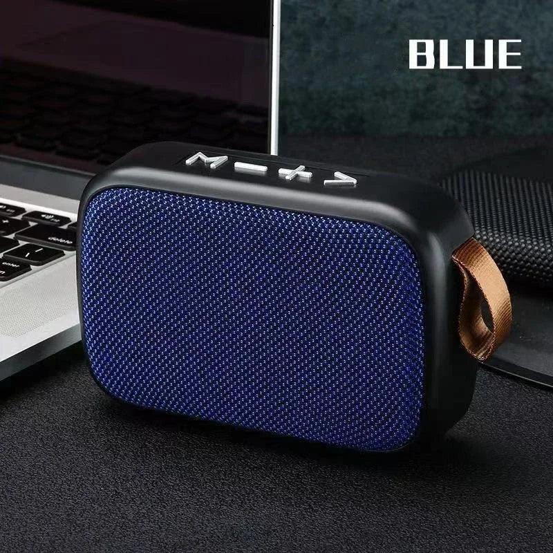 Enceinte Bluetooth portable bleue avec boutons de contrôle, posée à côté d'un ordinateur portable