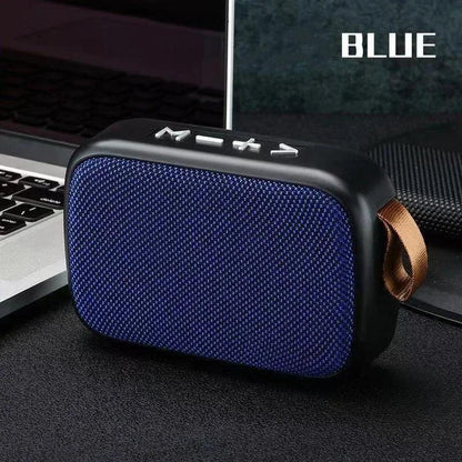 Enceinte Bluetooth portable bleue avec boutons de contrôle, posée à côté d'un ordinateur portable
