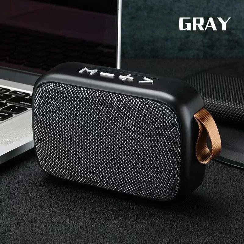 Enceinte Bluetooth portable grise avec boutons de volume et mode, design compact avec lanière