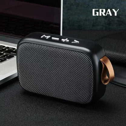 Enceinte Bluetooth portable grise avec boutons de volume et mode, design compact avec lanière