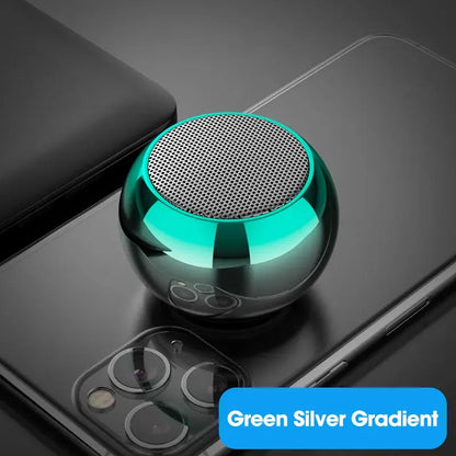 Mini enceinte portable ronde vert argent posé sur un smartphone noir avec triple caméra