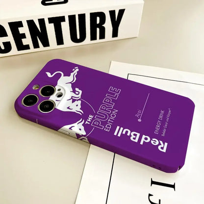Coque de téléphone violette Red Bull The Purple Edition avec logo taureaux blancs sur table avec livres