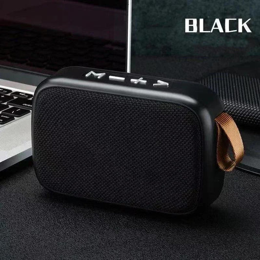 Enceinte Bluetooth noire compacte avec boutons de contrôle, posée près d'un ordinateur portable