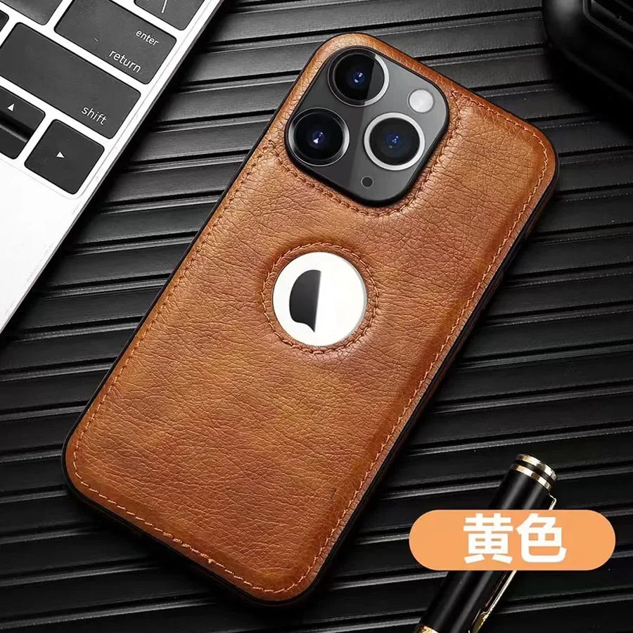 Coque de téléphone en cuir marron avec triple caméra sur fond noir à côté d'un clavier et d'un stylo
