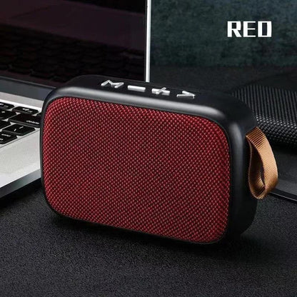 enceinte Bluetooth portable rouge avec bouton de contrôle posée à côté d'un ordinateur portable sur bureau