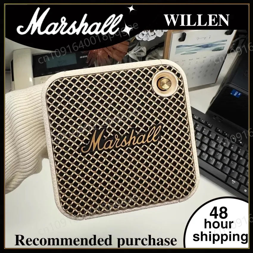 Enceinte Bluetooth Marshall Willen blanche au design rétro tenue à la main sur un bureau avec clavier