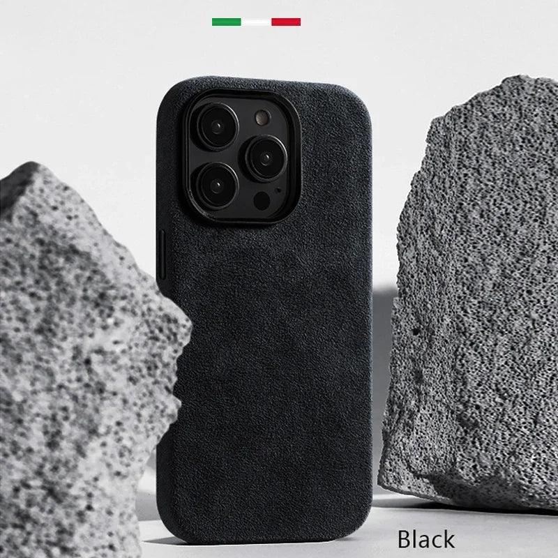 Coque de téléphone noire en suédine avec triple caméra, posée entre deux pierres texturées grises