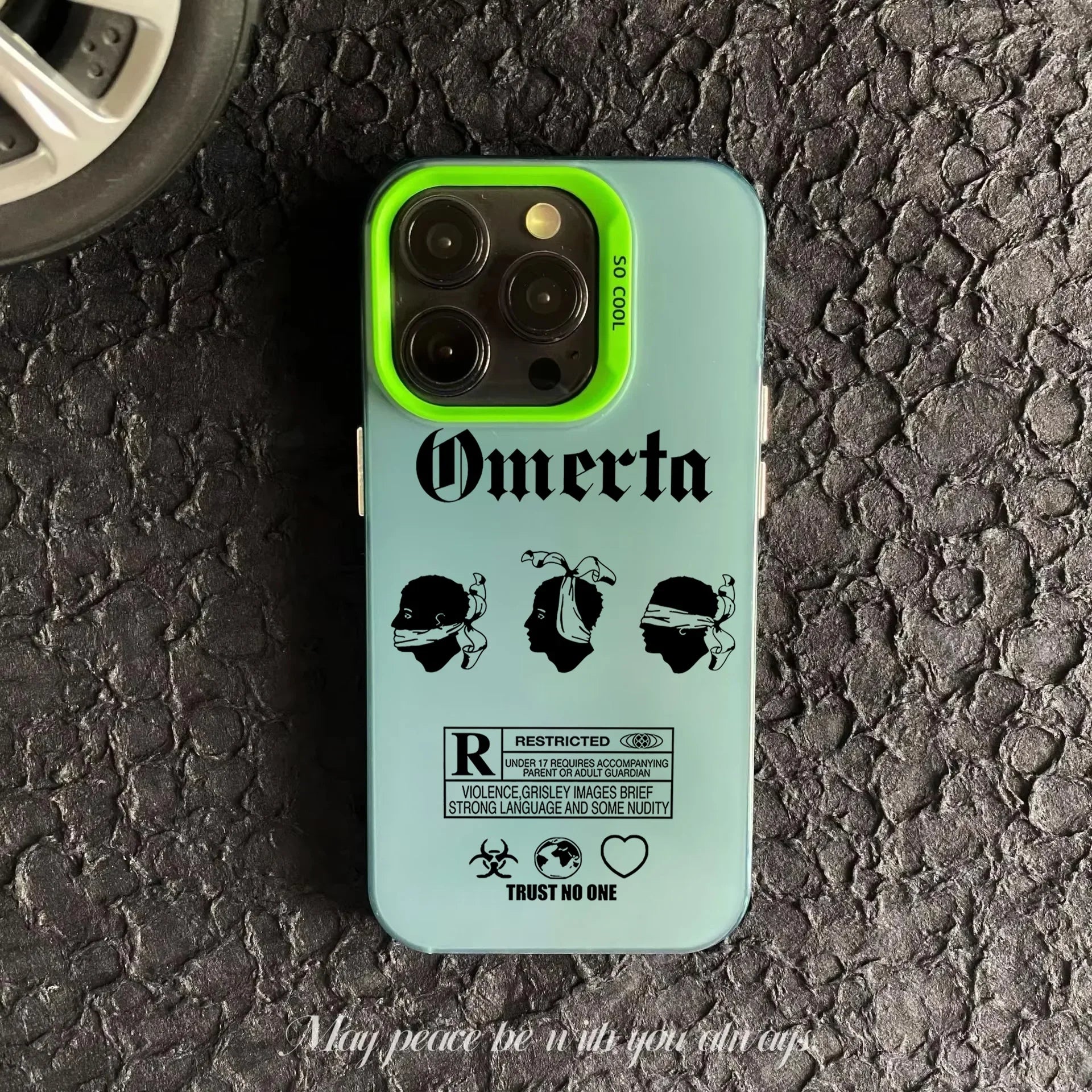 Coque iPhone bleue avec contours verts, illustration Omerta et message Trust No One sur surface asphaltée